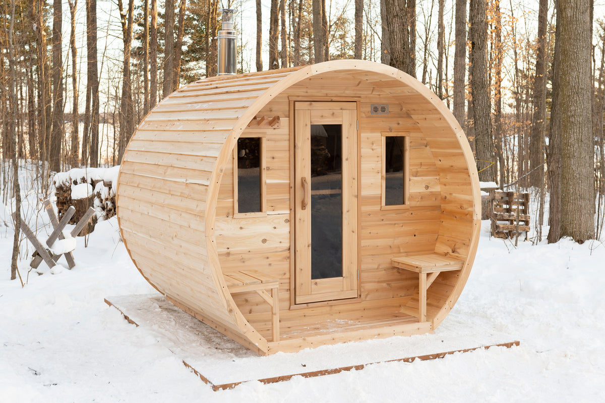 CT Elation cedar barrel sauna, three-quarter exterior view in a winter woodland