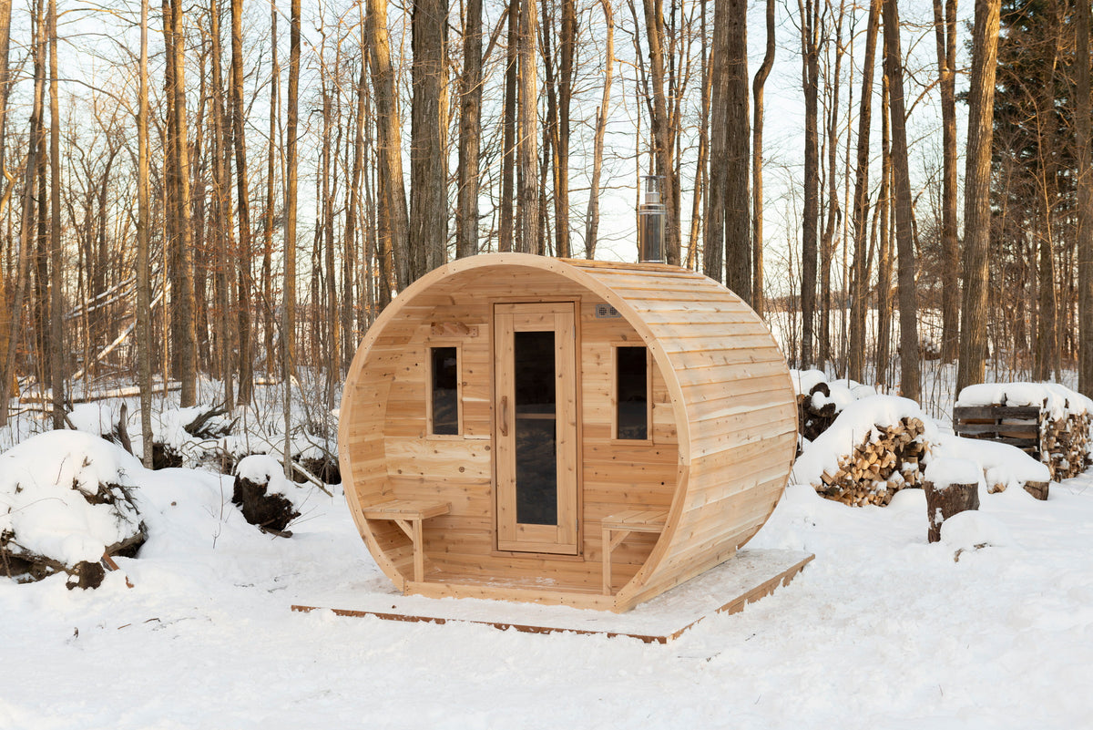 CT Elation sauna in the snow beside a stacked firewood pile