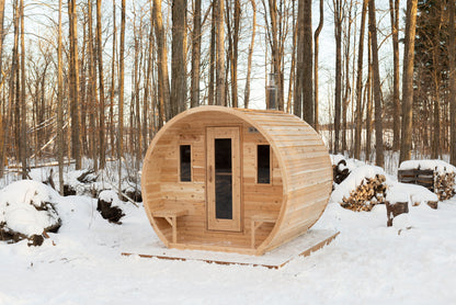 CT Elation sauna in the snow beside a stacked firewood pile
