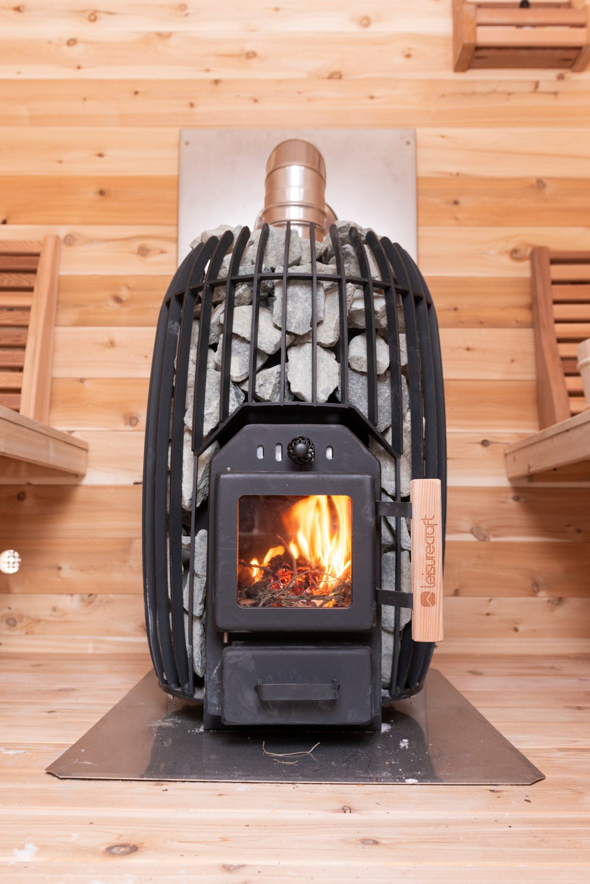 CT Elation sauna wood stove with a fire burning behind the stone-topped guard
