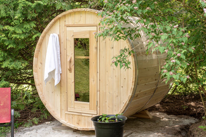 CT Harmony barrel sauna angled front view with a white towel on the door frame and a potted plant beside it