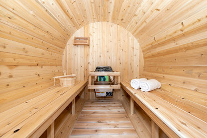 CT Harmony barrel sauna interior looking down the length of the barrel to the heater with facing cedar benches and folded towels