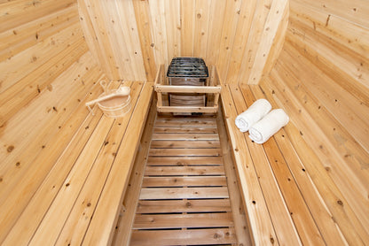 CT Harmony barrel sauna interior from the upper bench showing the heater, cedar bucket and ladle and rolled towels
