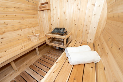 CT Harmony barrel sauna interior corner view with the electric heater on its guard rail and folded white towels on the bench
