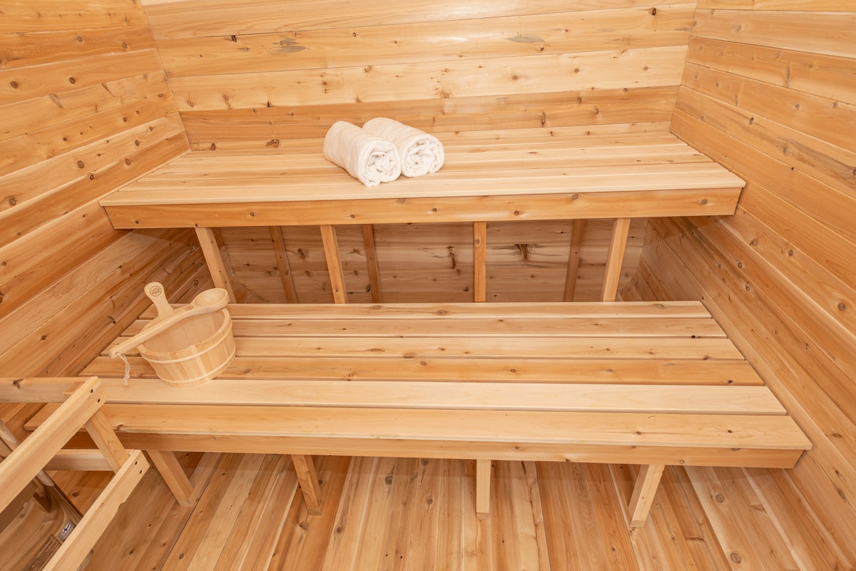 CT Luna sauna interior showing upper and lower Eastern White Cedar benches with rolled towels and a cedar bucket and ladle