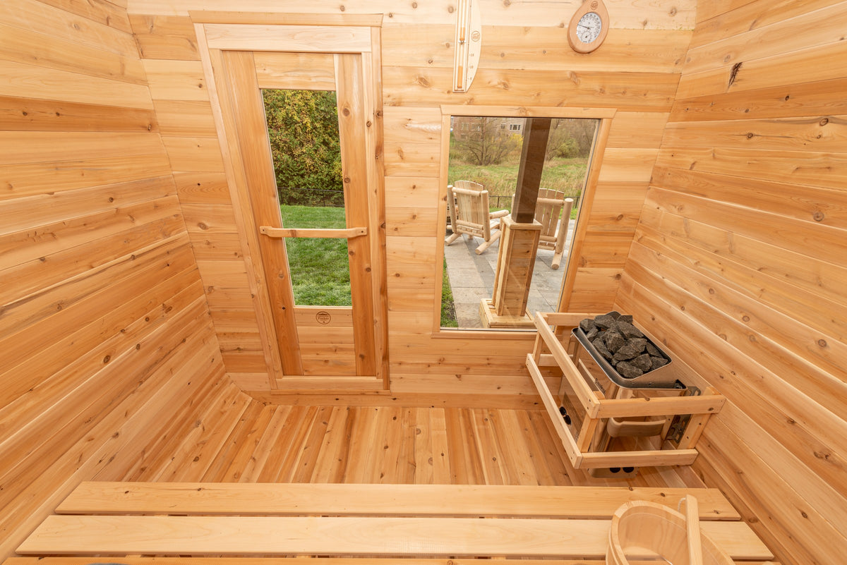 CT Luna sauna interior facing the door and window wall with the electric heater on its cedar stand and slatted floor