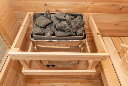 Close-up of the CT Luna electric sauna heater loaded with sauna stones behind its cedar safety guard rail