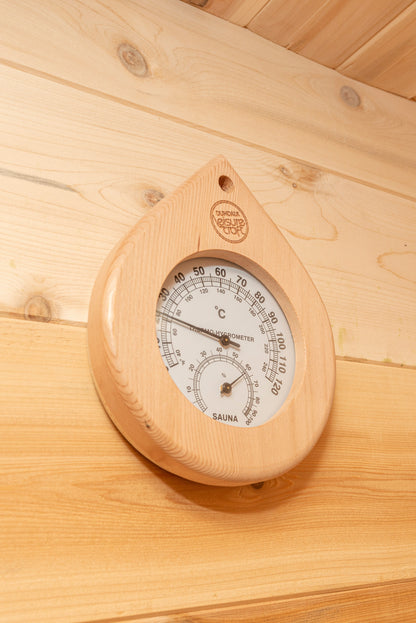 Close-up of the teardrop-shaped cedar thermometer and hygrometer mounted on the CT Luna sauna wall