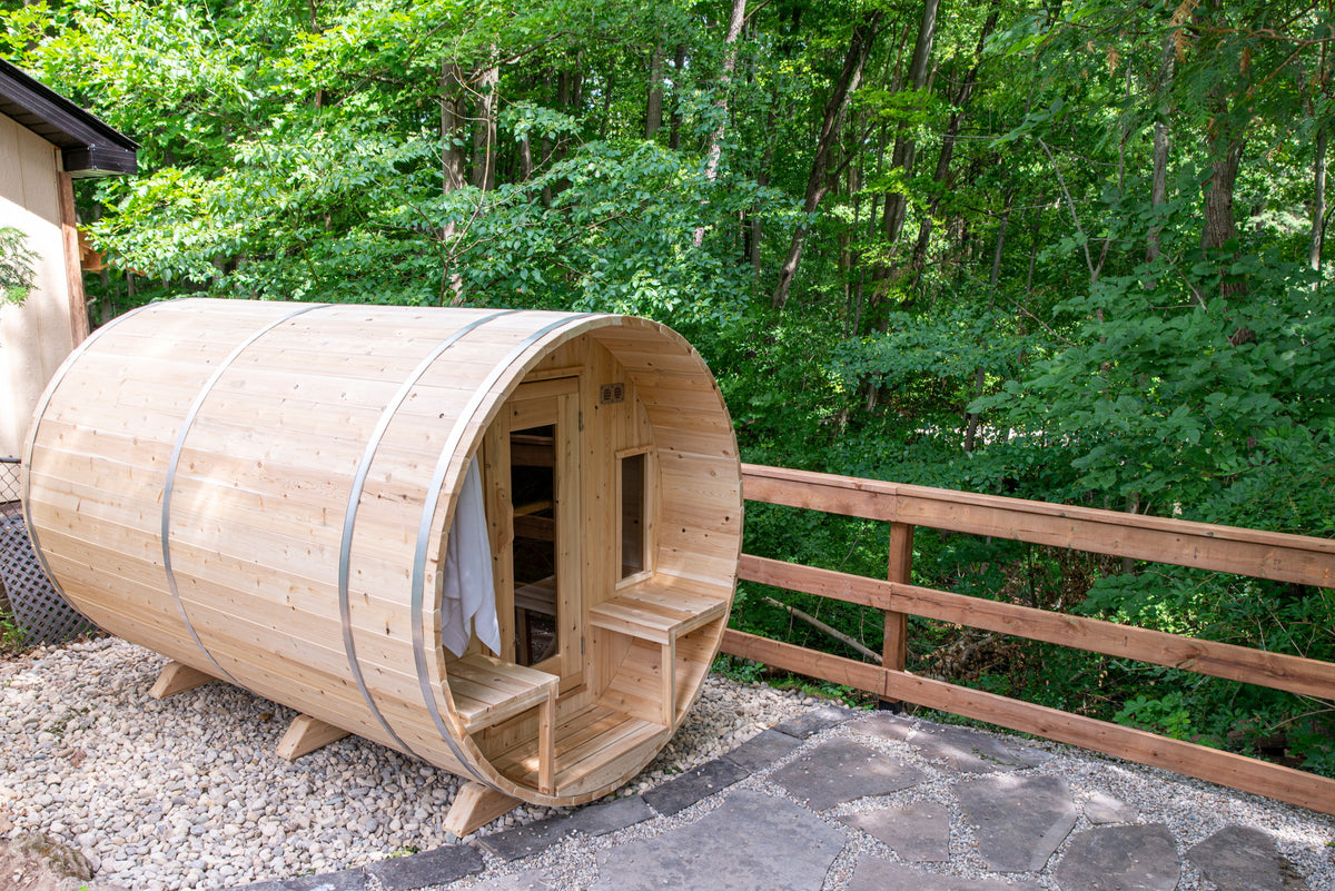 CT Tranquility barrel sauna in Eastern White Cedar, three-quarter view on a wooded stone pad