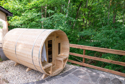 CT Tranquility barrel sauna in Eastern White Cedar, three-quarter view on a wooded stone pad