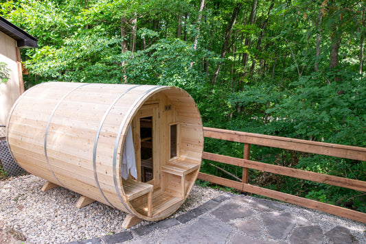 CT Tranquility barrel sauna in Eastern White Cedar, three-quarter view on a wooded stone pad