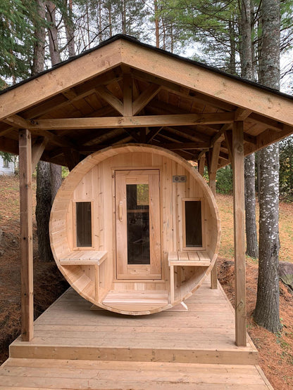 CT Tranquility barrel sauna installed under a timber pavilion in a wooded setting