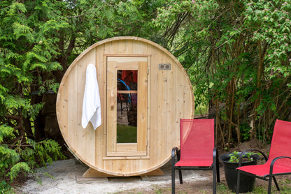 CT Harmony barrel sauna front elevation in Eastern White Cedar with a window door, white towel hung on the frame, and red patio chairs alongside